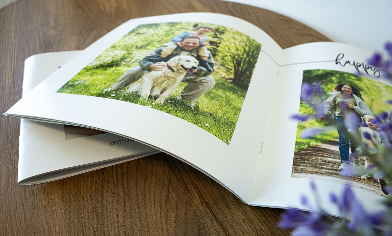 Un álbum de fotos abierto con imágenes de una familia al aire libre. A la izquierda, un hombre con un perro y sus hijos en el campo. A la derecha, una mujer paseando con sus hijos.