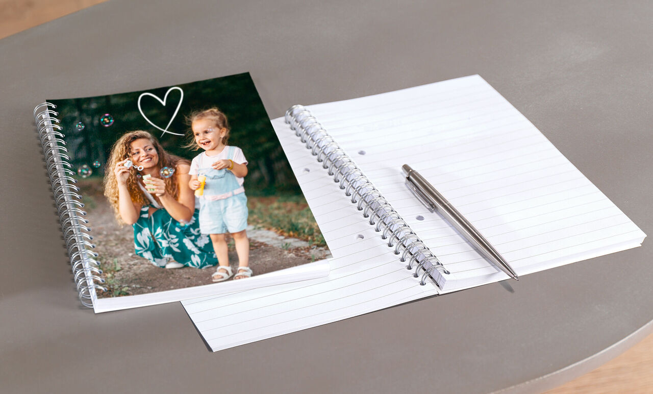 Una mujer sostiene una cámara con un niño a su lado, visible en un libro de fotos.
