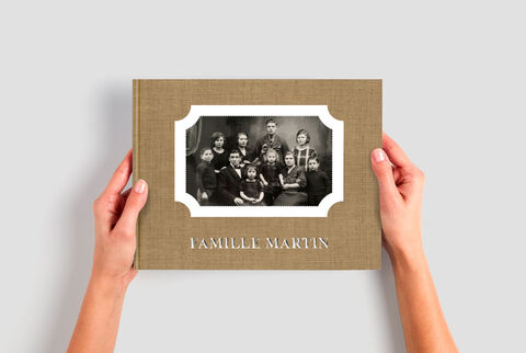 Una mano sostiene un álbum CEWE titulado 'Familia Martín' con una foto familiar en blanco y negro en la portada.