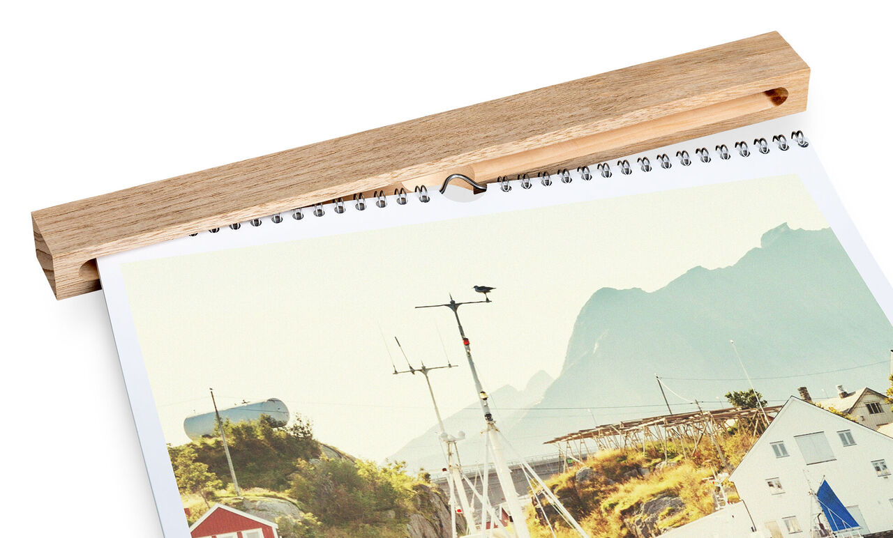 Un calendario CEWE muestra un paisaje costero con montañas al fondo.