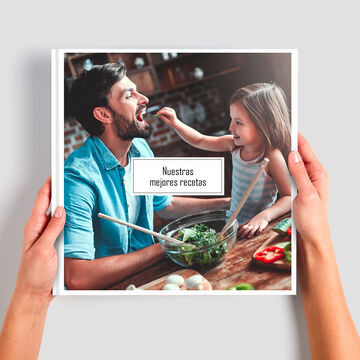 Una persona presenta un álbum CEWE con recetas.