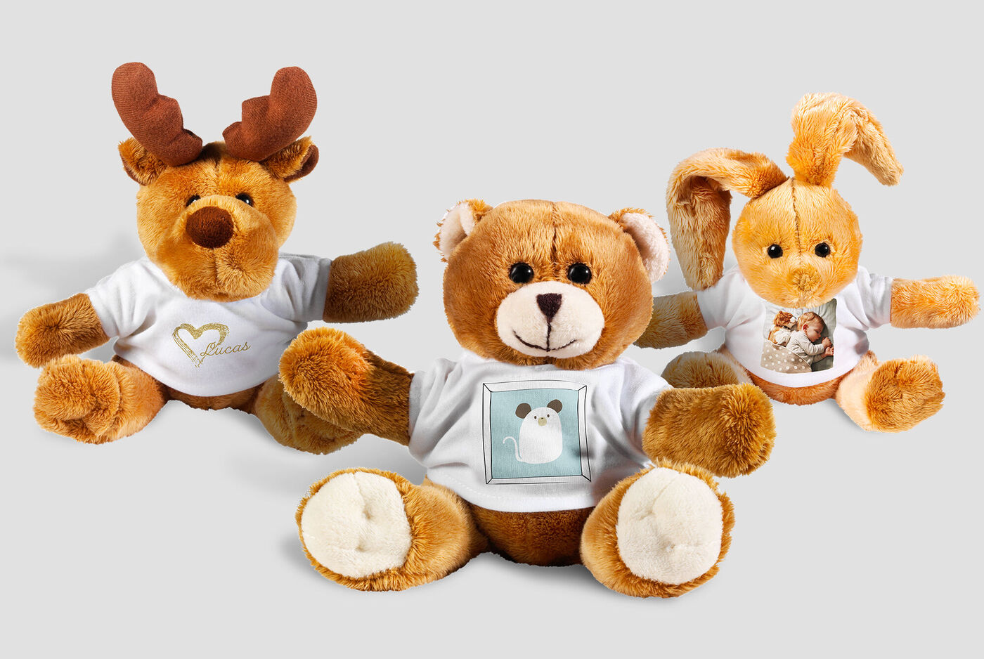 Tres suaves peluches: un reno, un oso y un conejo, usando camisetas personalizadas con fotos.