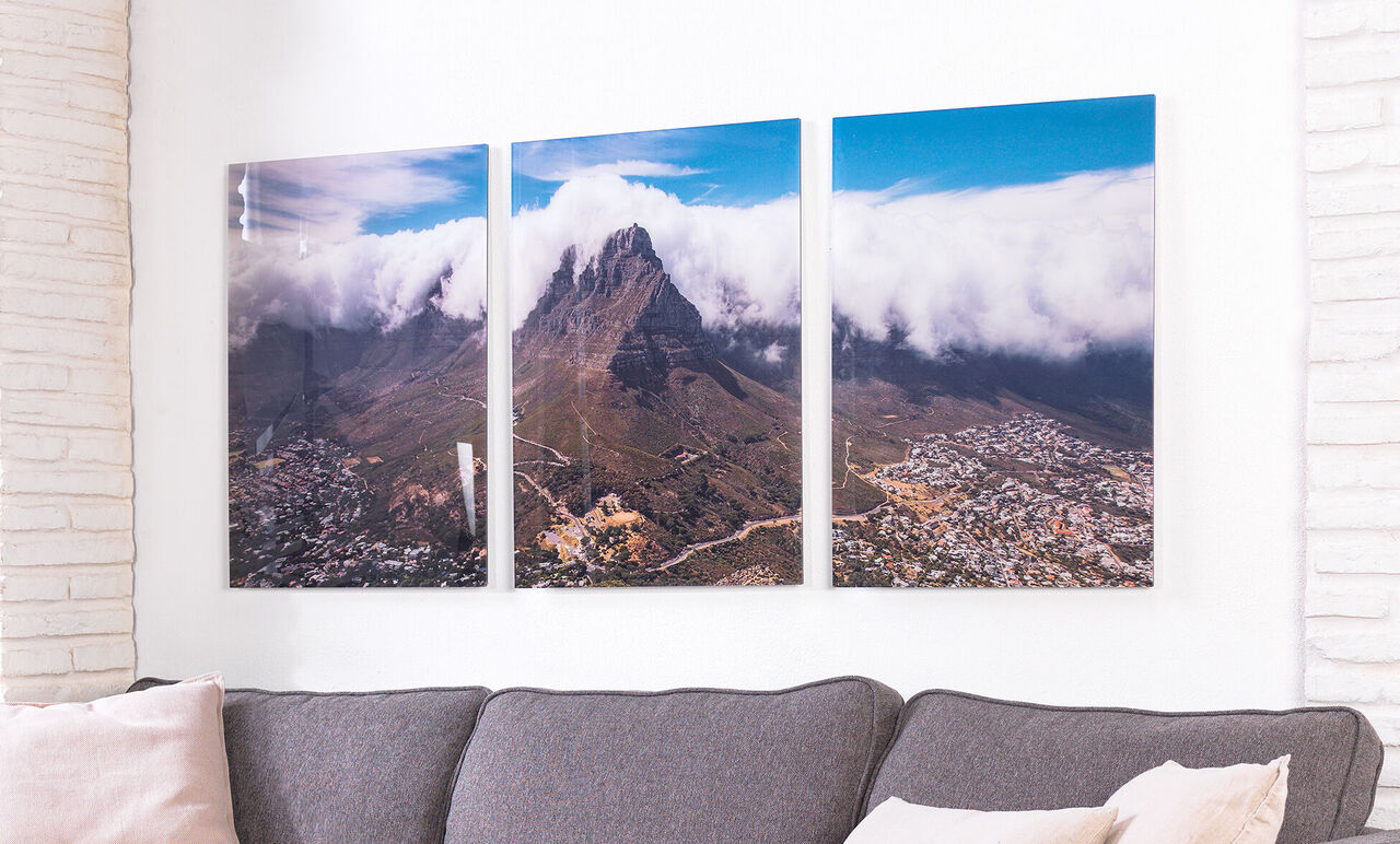 Tres imágenes conectadas de un paisaje montañoso con nubes al fondo.