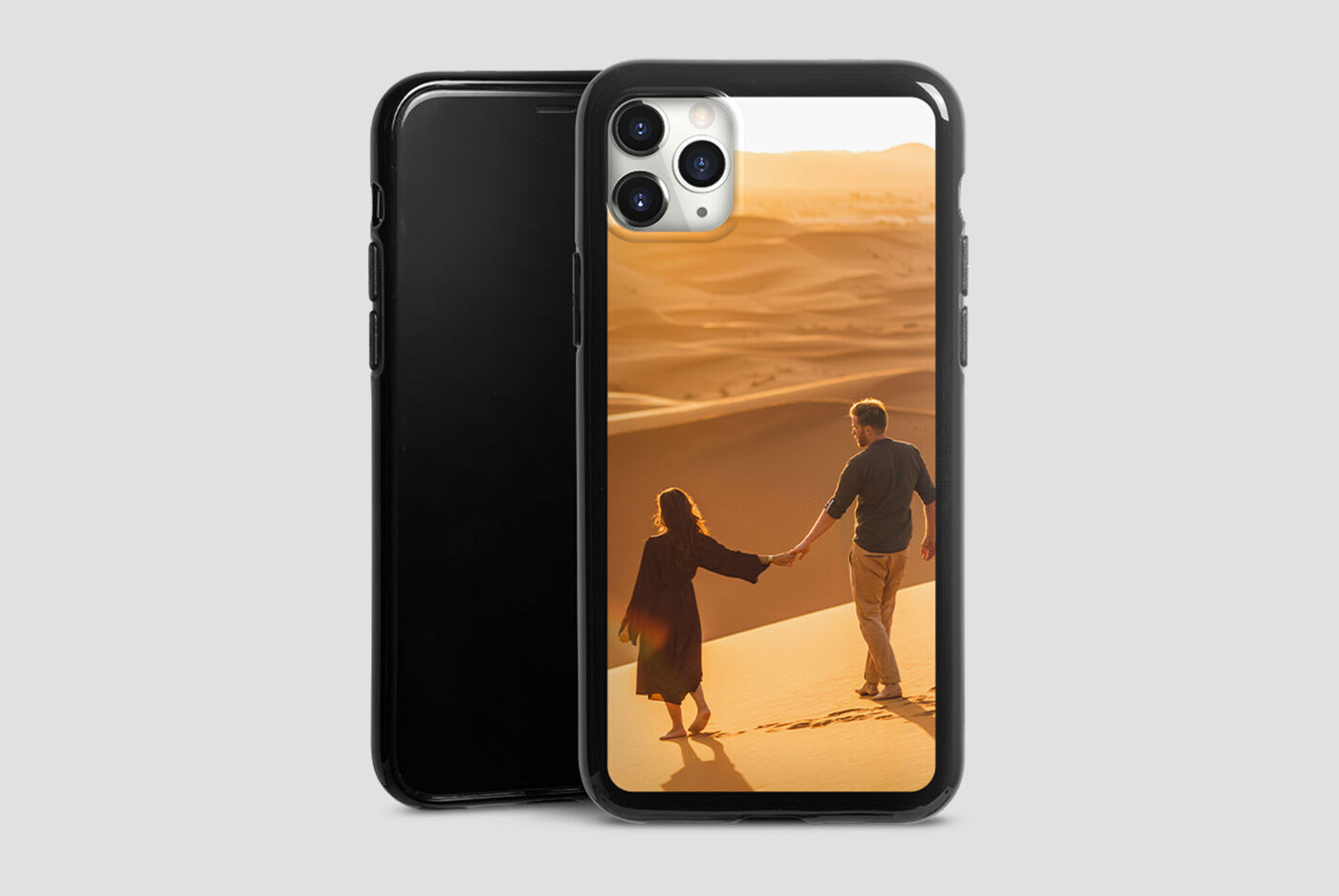 Pareja camina de la mano sobre dunas de arena al atardecer.