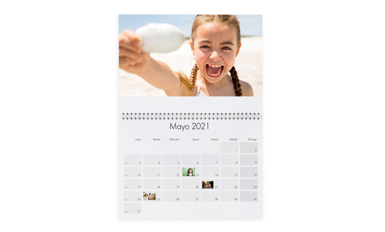Un encantador calendario CEWE para mayo 2021 con una persona feliz en la playa sosteniendo una concha.