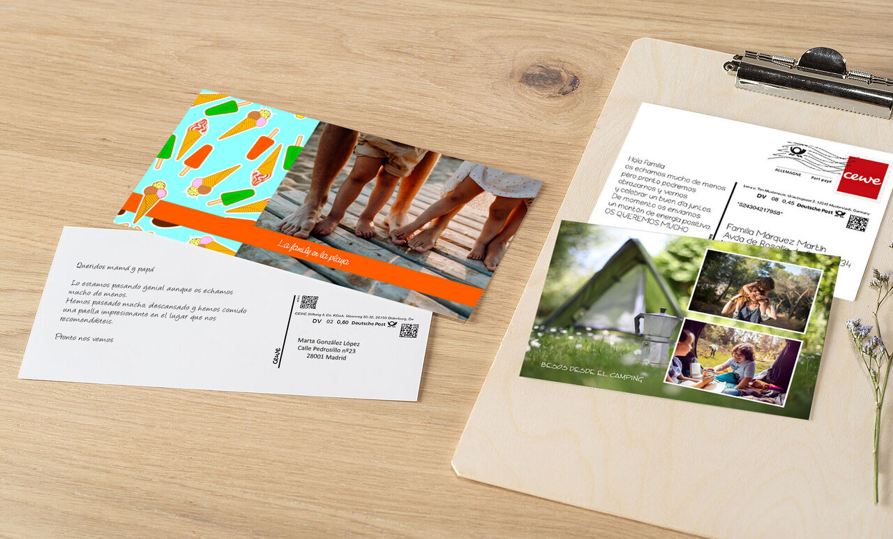 Dos tarjetas CEWE creativas en una mesa de madera, una con motivos de helados y la otra con una foto familiar y una tienda. ¡Perfectas para regalar!