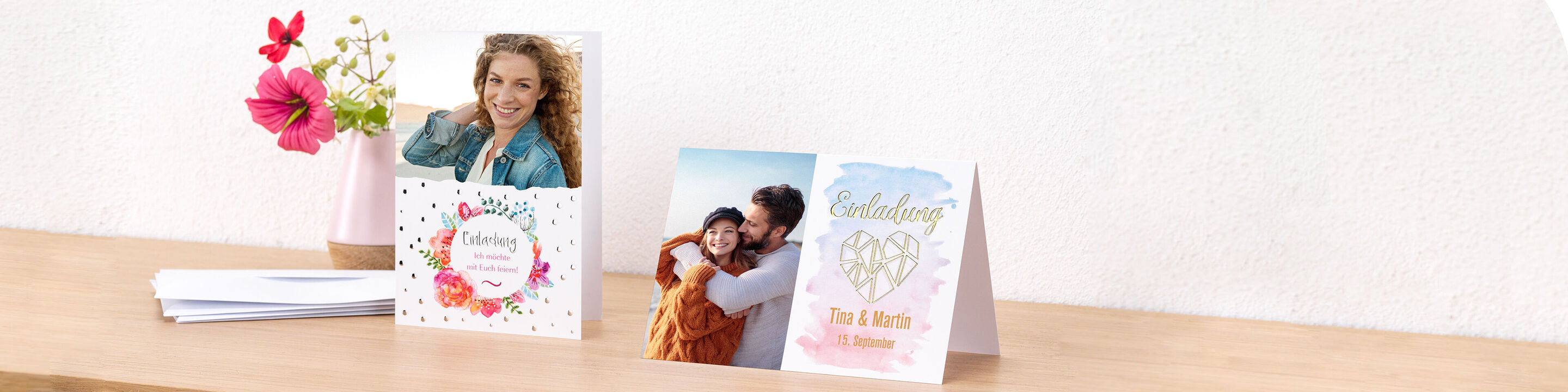 Tres tarjetas de saludo cuidadosamente diseñadas sobre una mesa de madera, rodeadas de una flor.