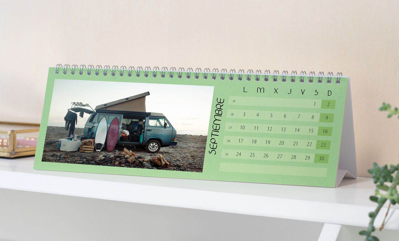 Un creativo calendario fotográfico muestra una furgoneta VW en la playa con tablas de surf.