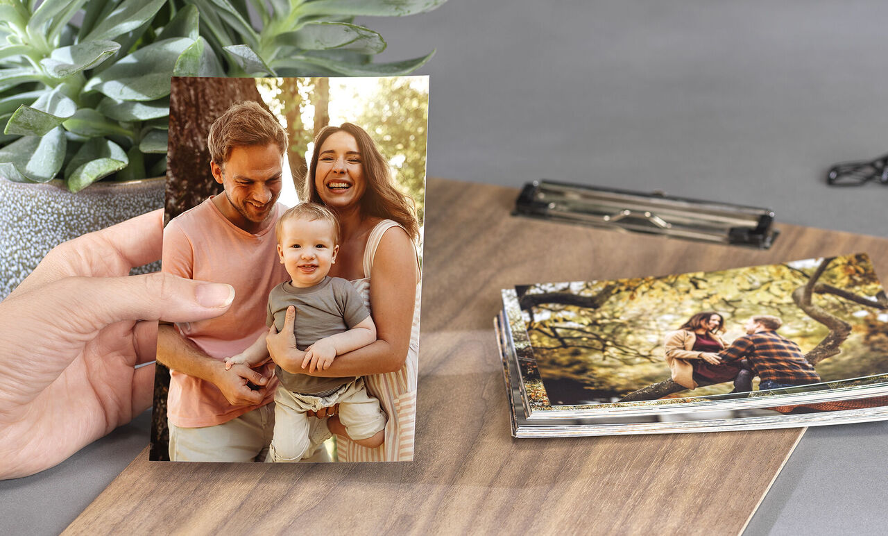foto tamaño 10x15 de unos padres con su familia y varios revelados amontonados en una mesa.