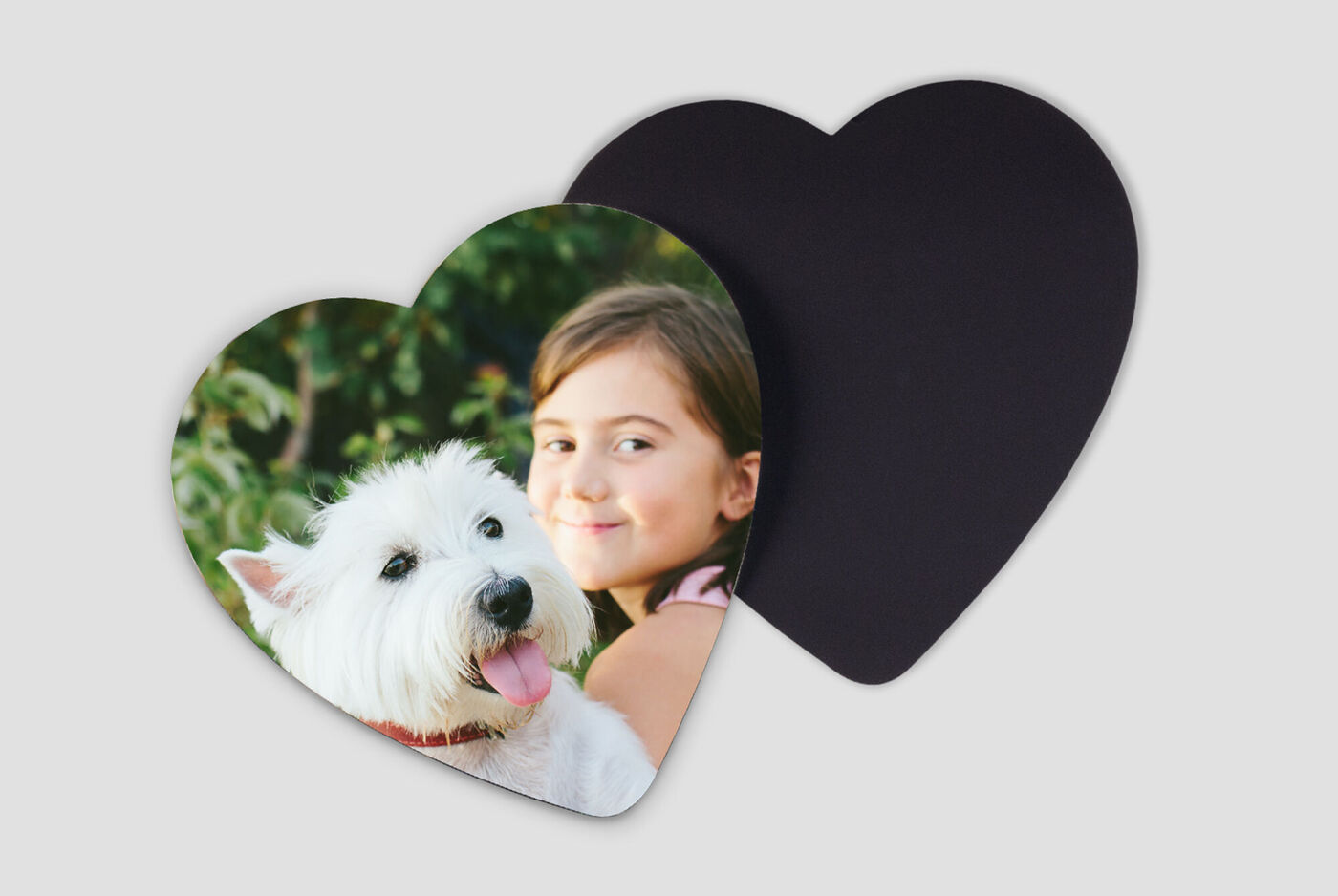 Un perro blanco con lengua rosa posa frente a una niña en una tarjeta en forma de corazón