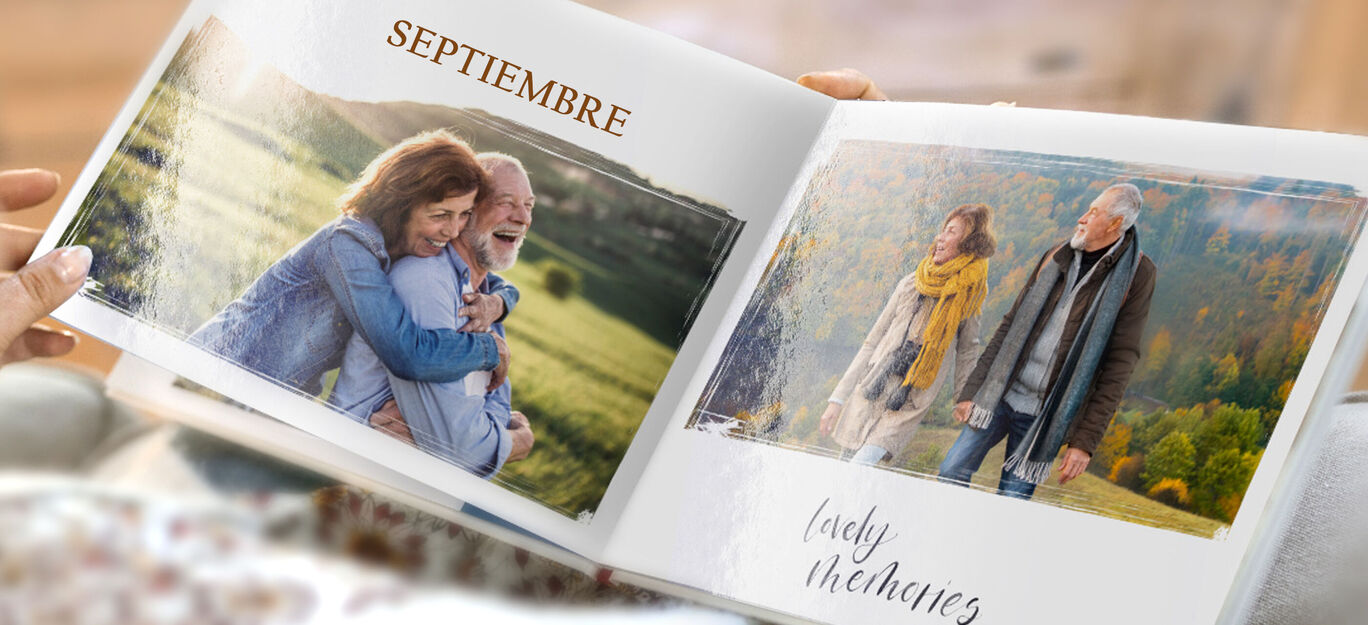 Dos personas hojean un fotolibro lleno de recuerdos al aire libre.