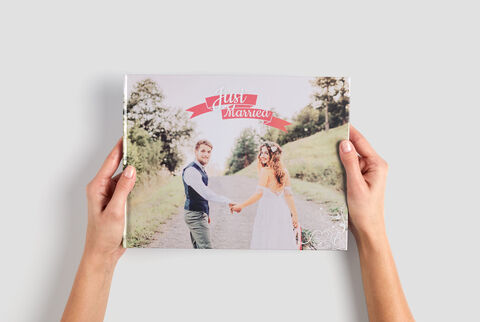 Una pareja sostiene un libro de fotos CEWE con su foto de boda en la portada.