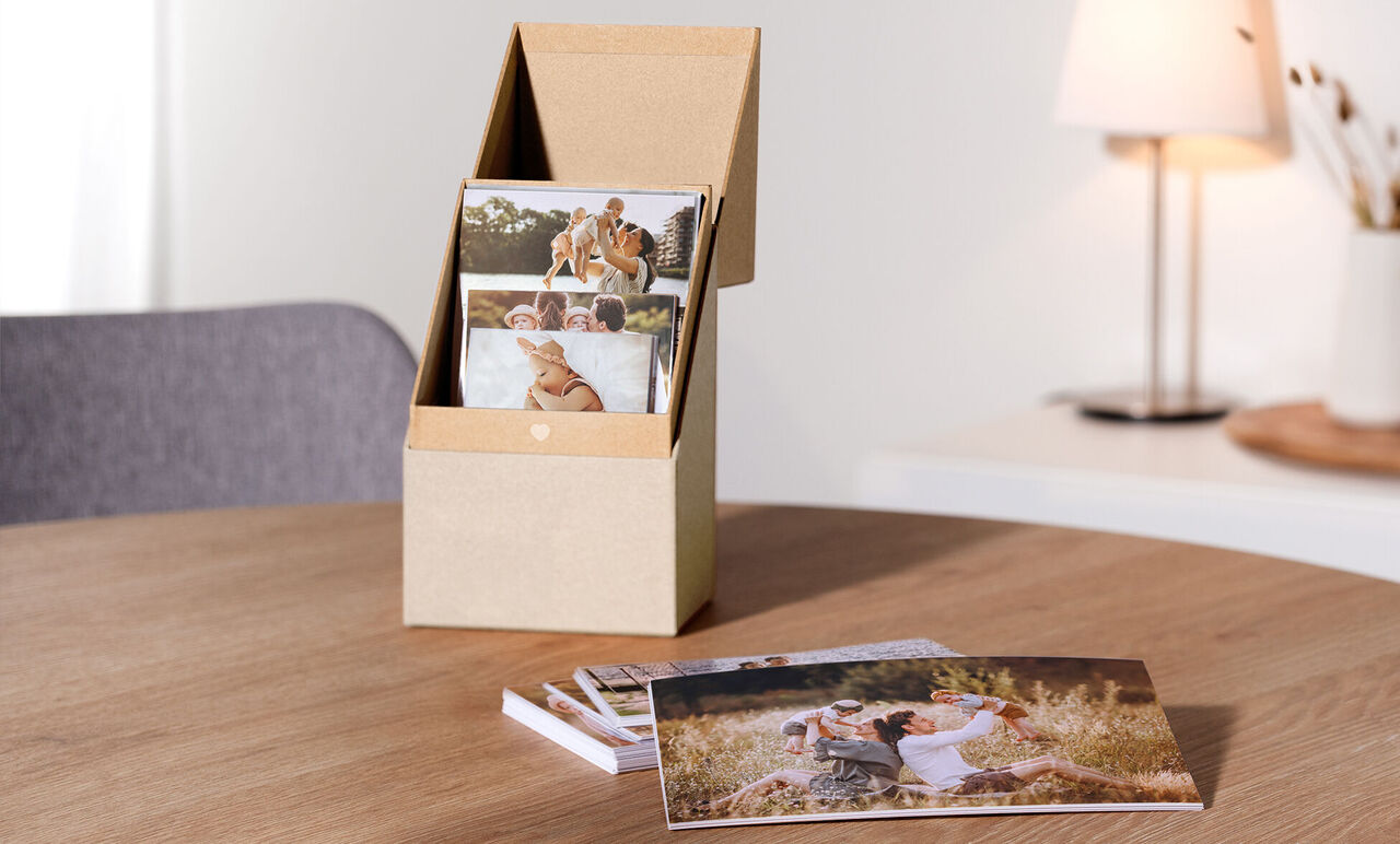 Una caja de almacenamiento con decoración para guardar tus fotos personales sobre una mesa de madera.