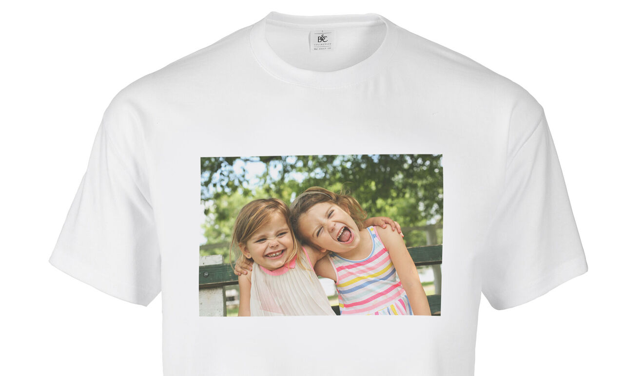 Dos niños en camisetas coloridas se abrazan felices al aire libre.