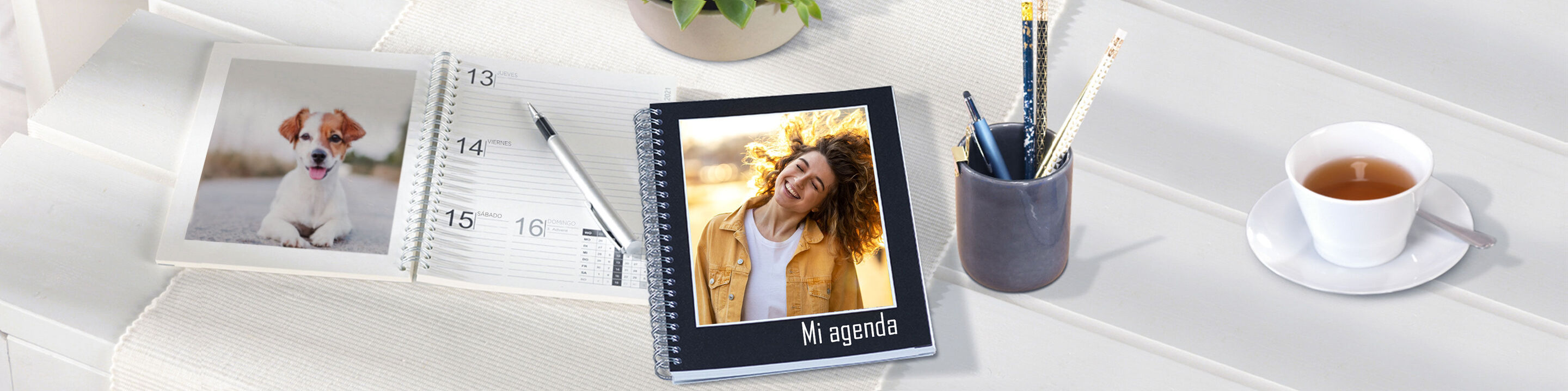 Una hermosa mesa con un calendario CEWE, una foto de un perro y una taza de café. Irradia una atmósfera creativa y personal.