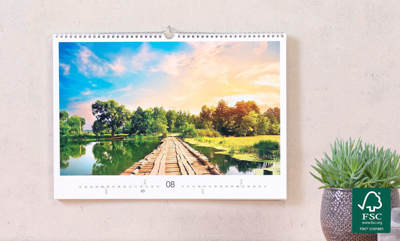 Un hermoso calendario de fotos muestra un paisaje pacífico con un muelle sobre un lago, rodeado de árboles y prados.