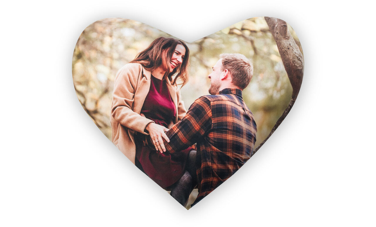 Una pareja enamorada sentada al aire libre, rodeada de árboles. Irradian alegría y afecto mientras se miran y disfrutan de su compañía.