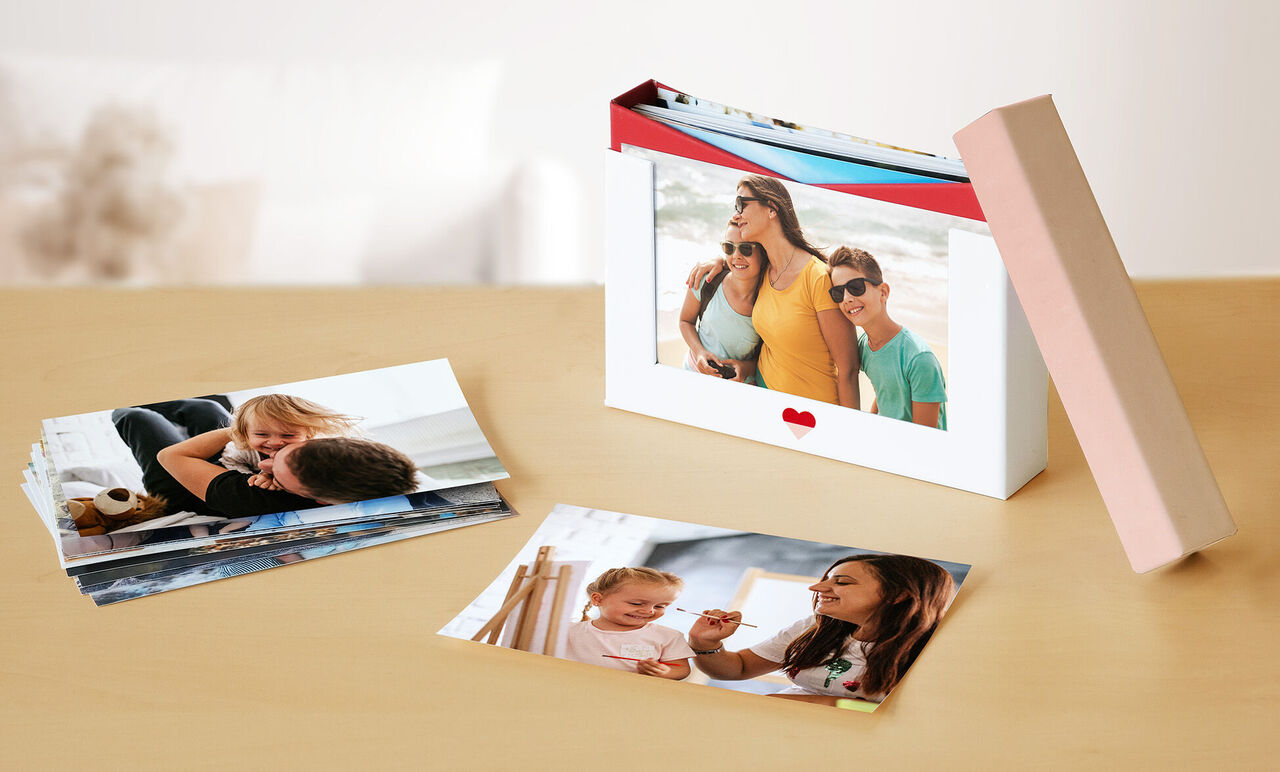 Revelados fotográficos sobre una mesa y una caja de almacenamiento para fotos.