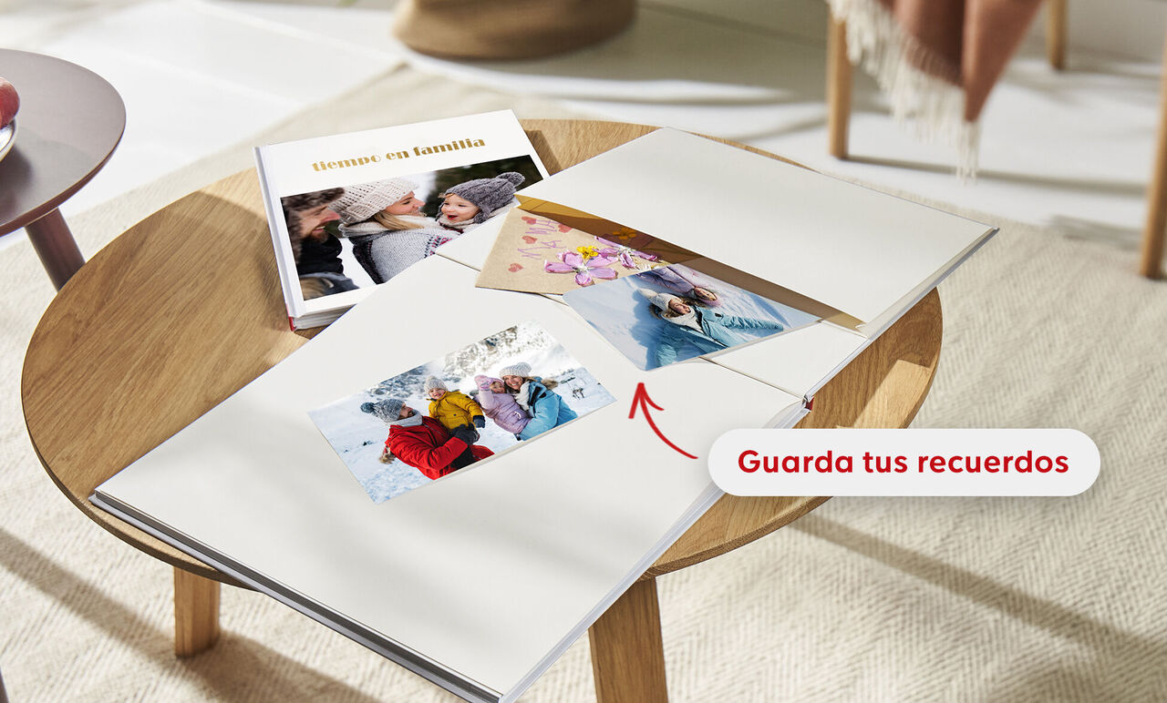 Dos CEWE FOTOLIBROS sobre una mesa, uno abierto con fotos de momentos felices en familia. Nota: "Guarda tus recuerdos".