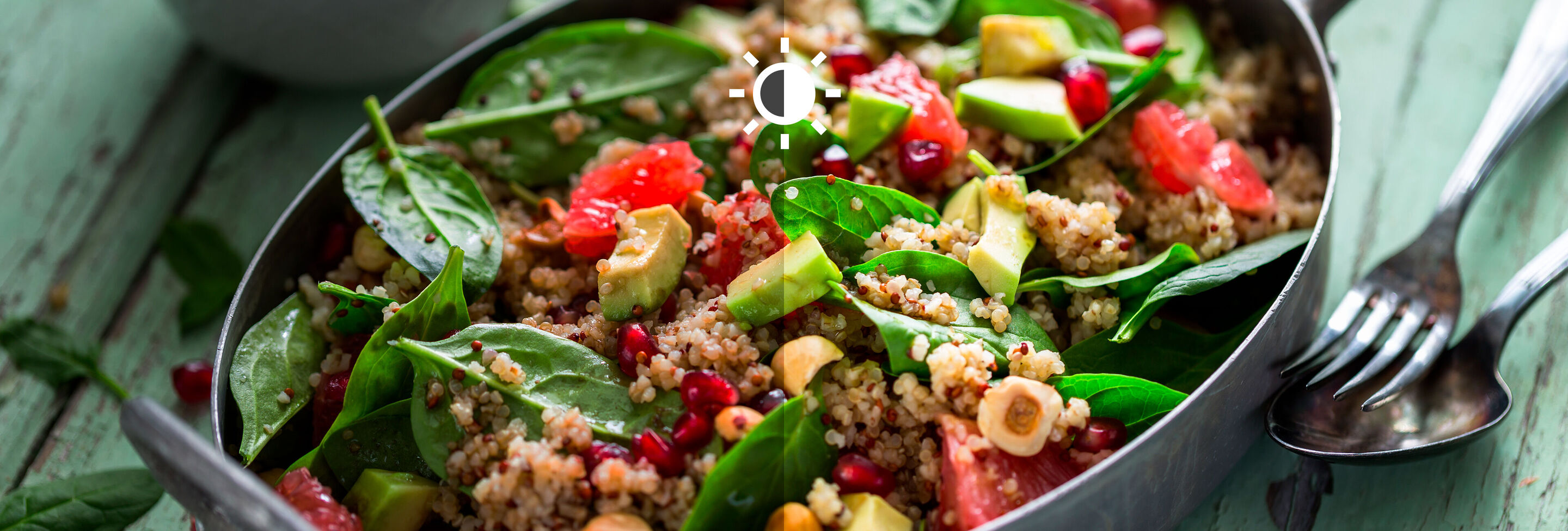 Un tazón de ensalada de quinoa colorido con espinacas frescas, granos de granada y varias verduras.