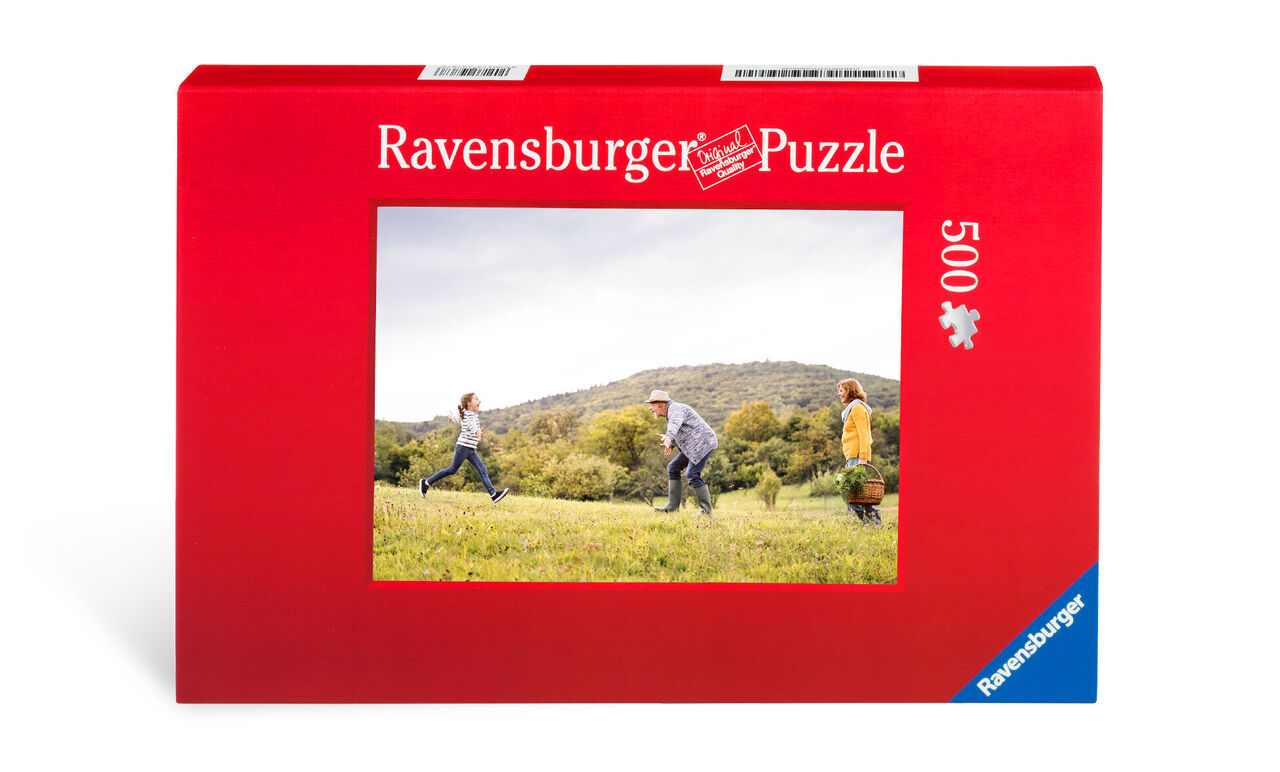 Una caja roja con el rompecabezas Ravensburger, que muestra una escena alegre de tres niños jugando al aire libre.