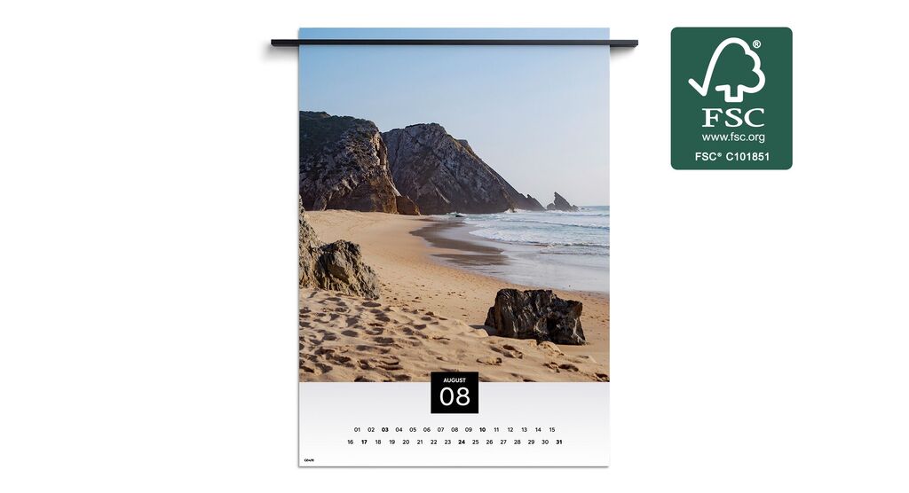 Paisaje costero con rocas y suaves olas bajo un cielo azul, mostrado en un calendario mural de agosto