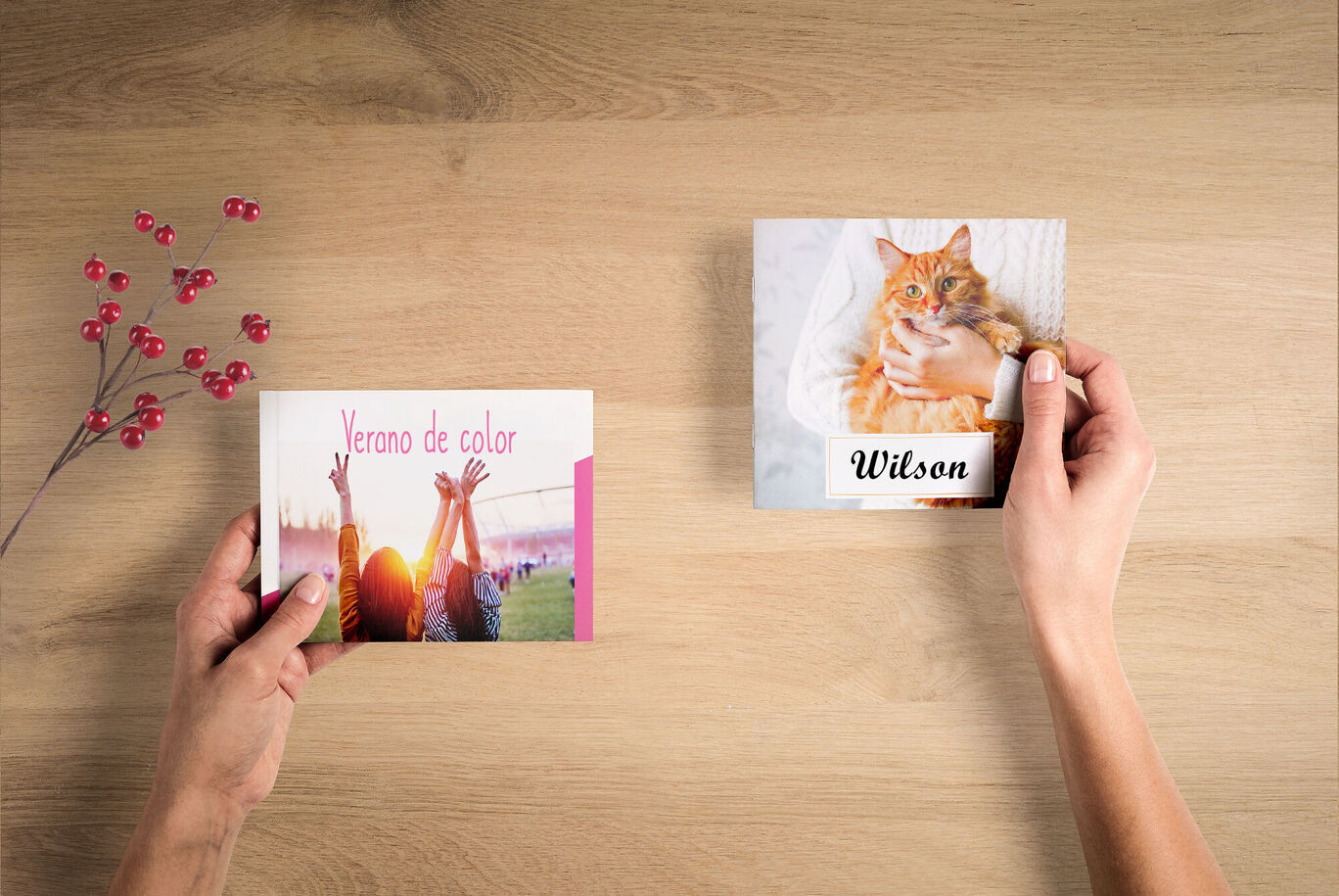 Dos personas sostienen un CEWE FOTOBUCH y una tarjeta CEWE con un gato.