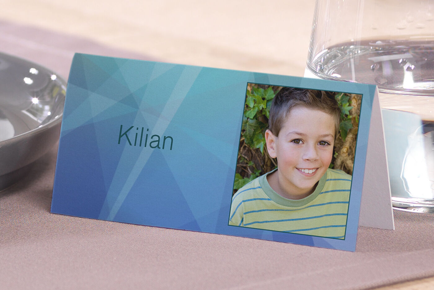 Tarjeta de mesa con el nombre Kilian sobre fondo geométrico azul.