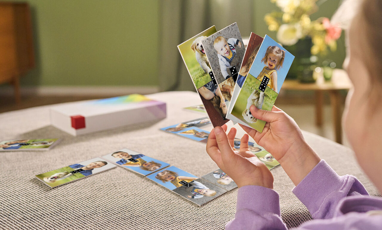 Un niño sostiene con cariño tarjetas con fotos familiares y motivos coloridos en sus manos.