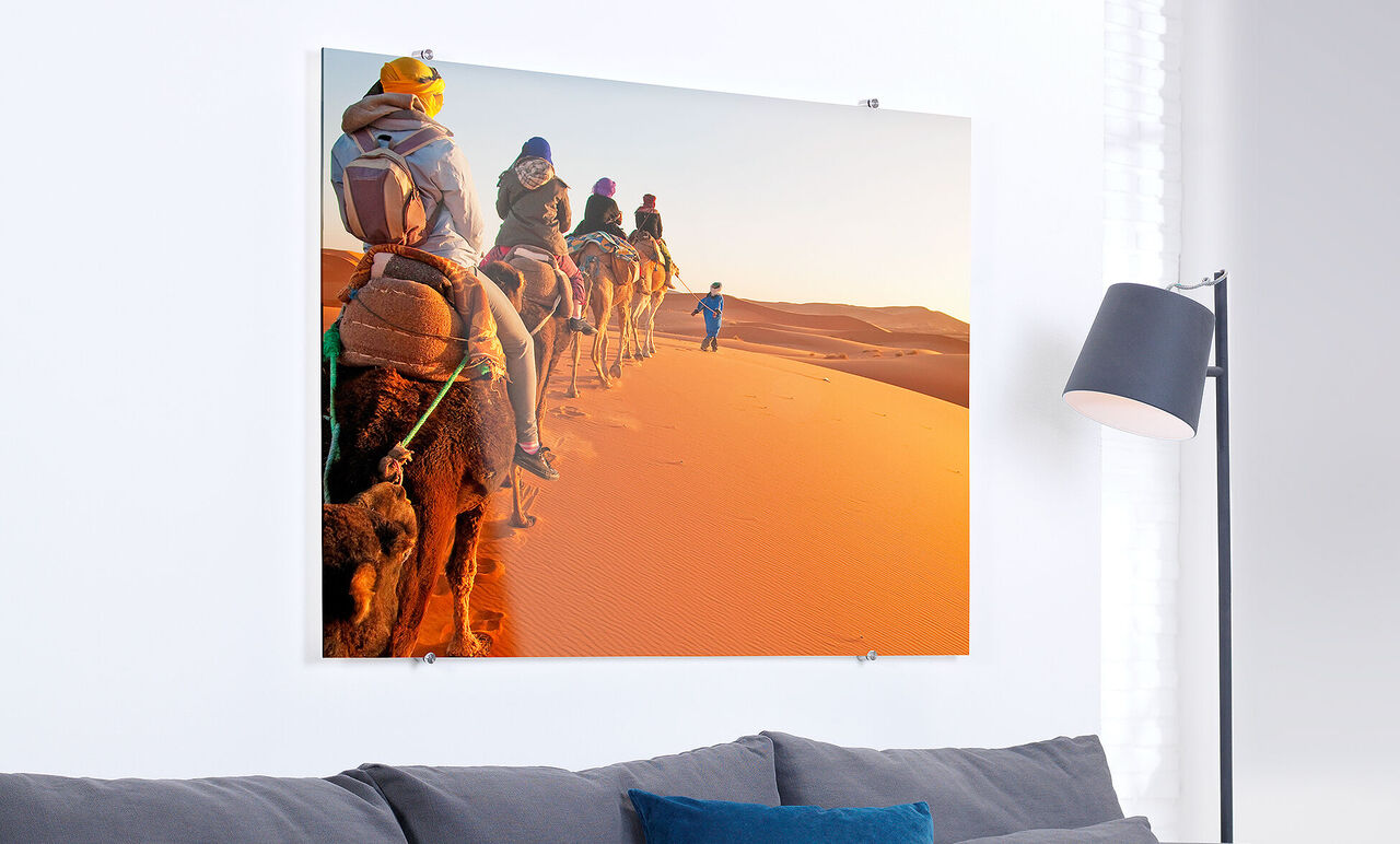 Personas montan camellos a través del desierto al atardecer, el paisaje cálido brilla.