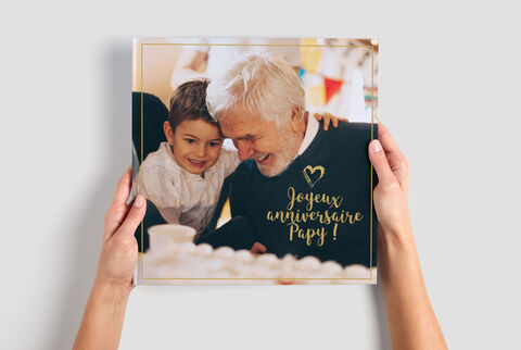Dos personas miran tiernamente un álbum decorado con '¡Feliz cumpleaños Papi!'.