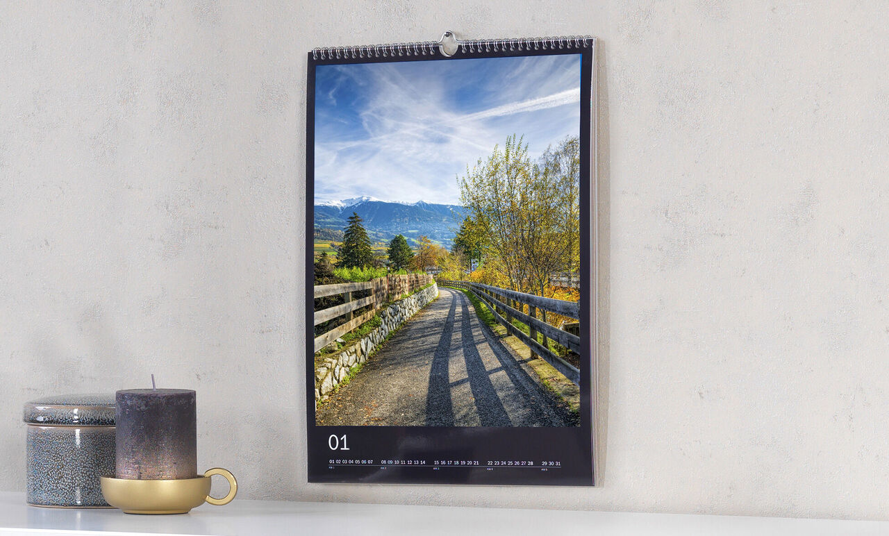 Imagen perfecta de un calendario colgado con un paisaje hermoso. La senda pasa entre árboles y praderas.