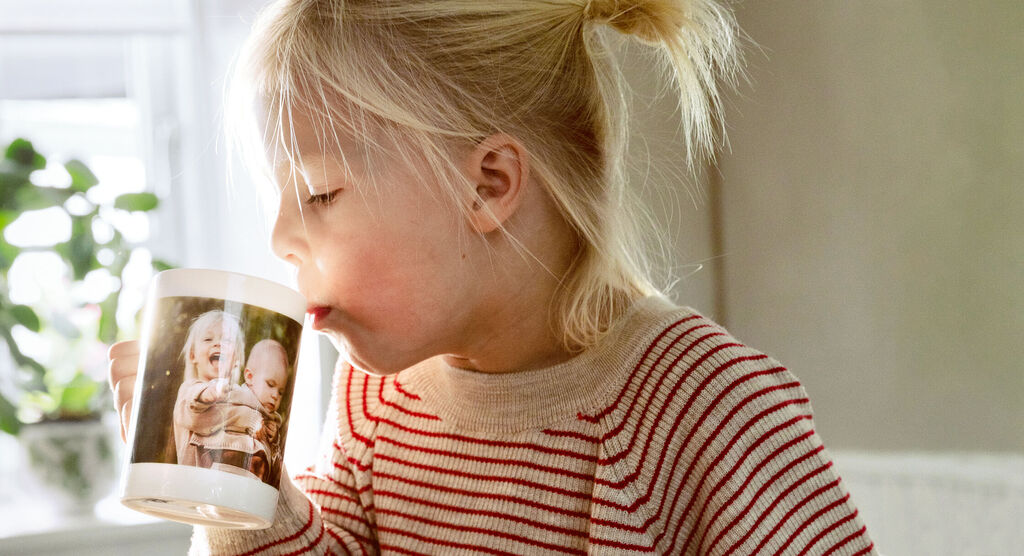 Un niño sostiene una taza personalizada con una foto.