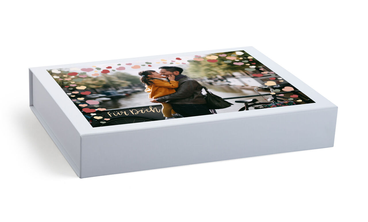 Una hermosa caja de CEWE FOTOBUCH con detalles coloridos en una mesa.