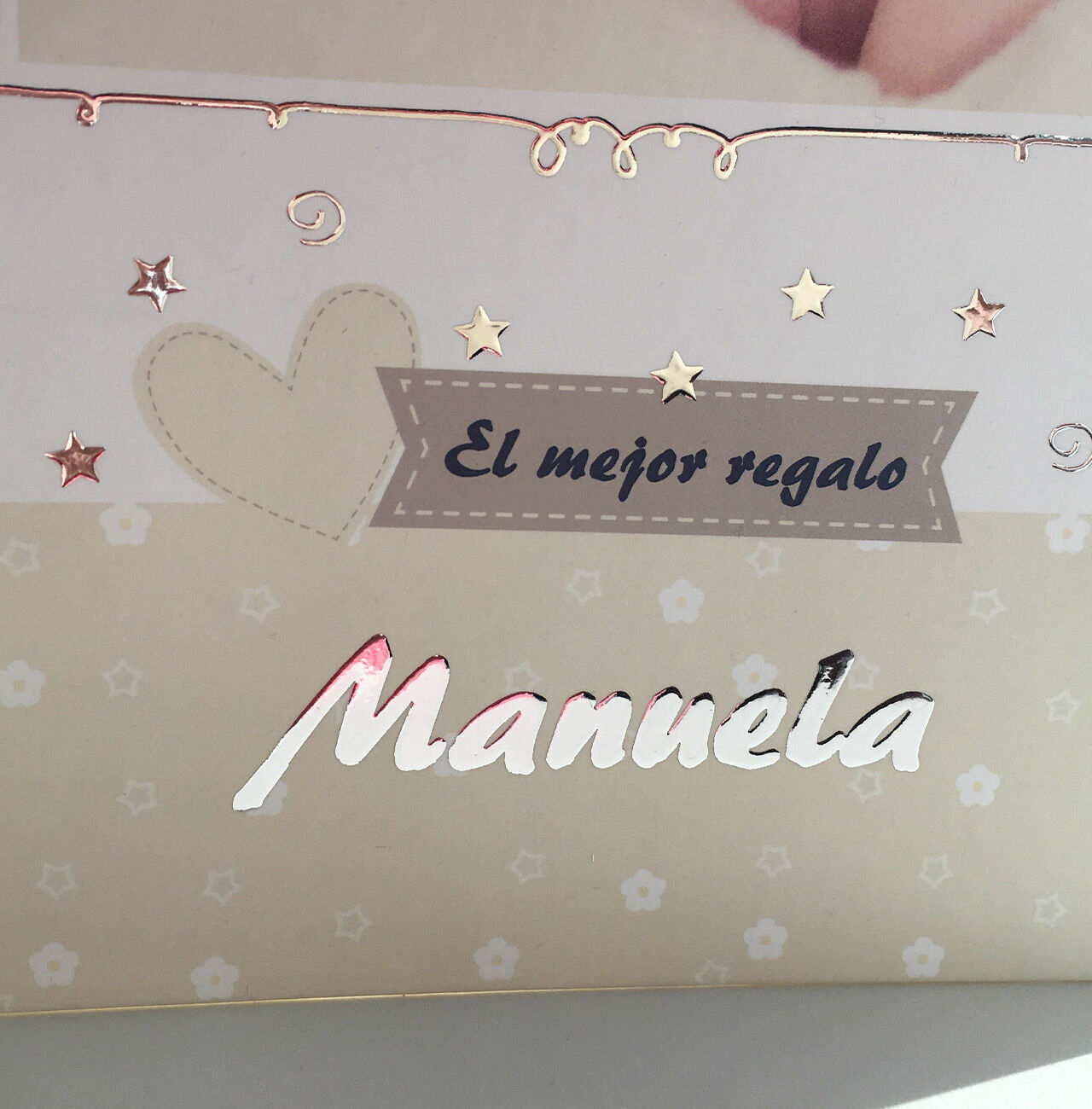 Un libro de fotos diseñado con cariño que lleva el nombre 'Manuela' y un corazón dorado en la portada.