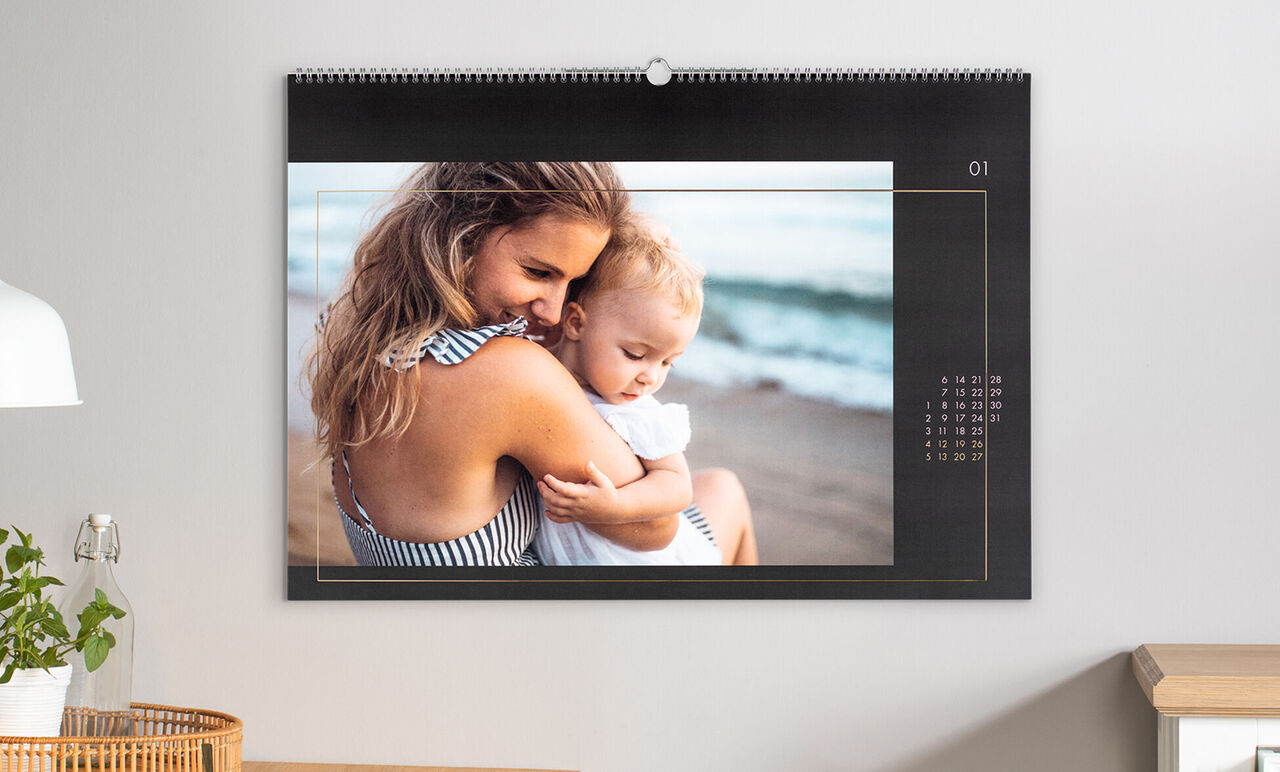 Una madre cariñosa sostiene a su hijo en la playa en un calendario fotográfico.