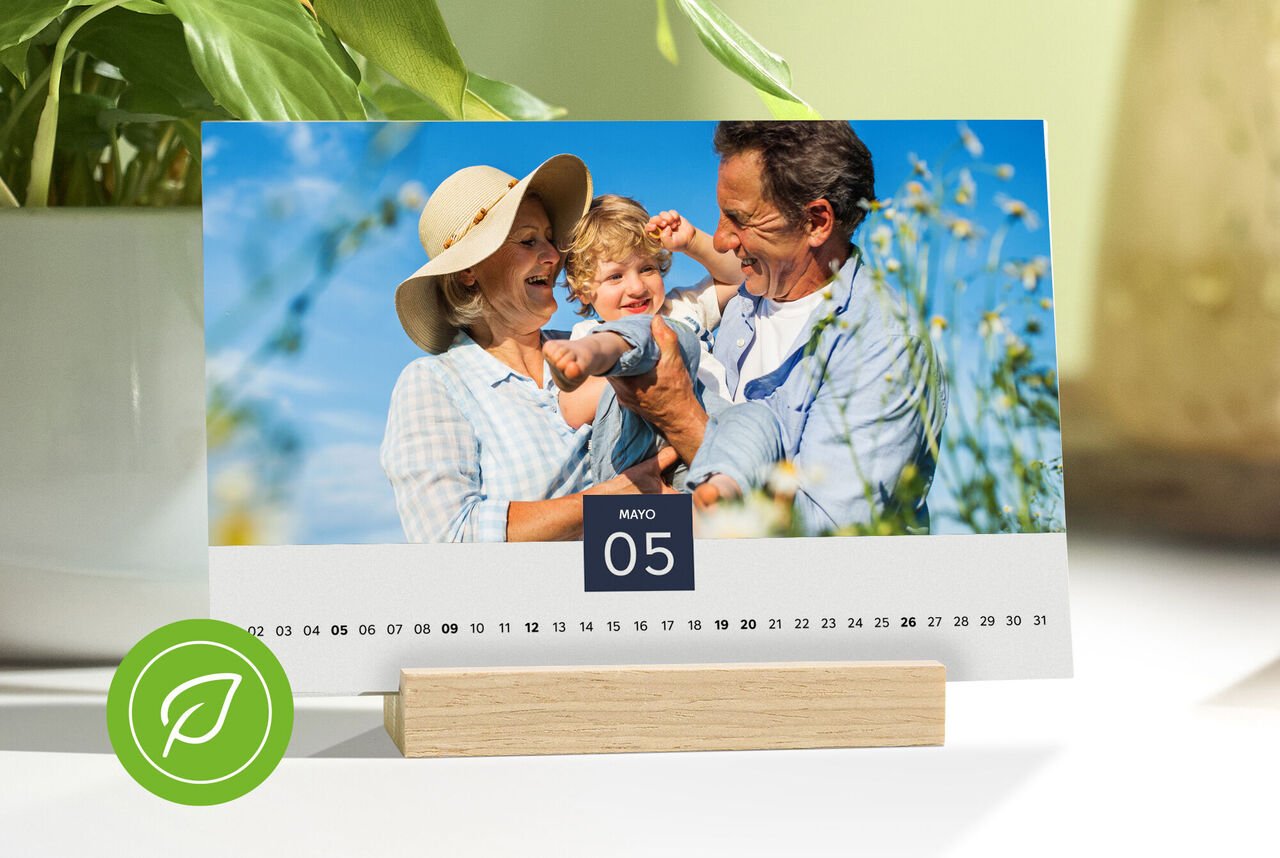 Una pareja feliz sostiene un bebé frente a un calendario que muestra el 5 de mayo.