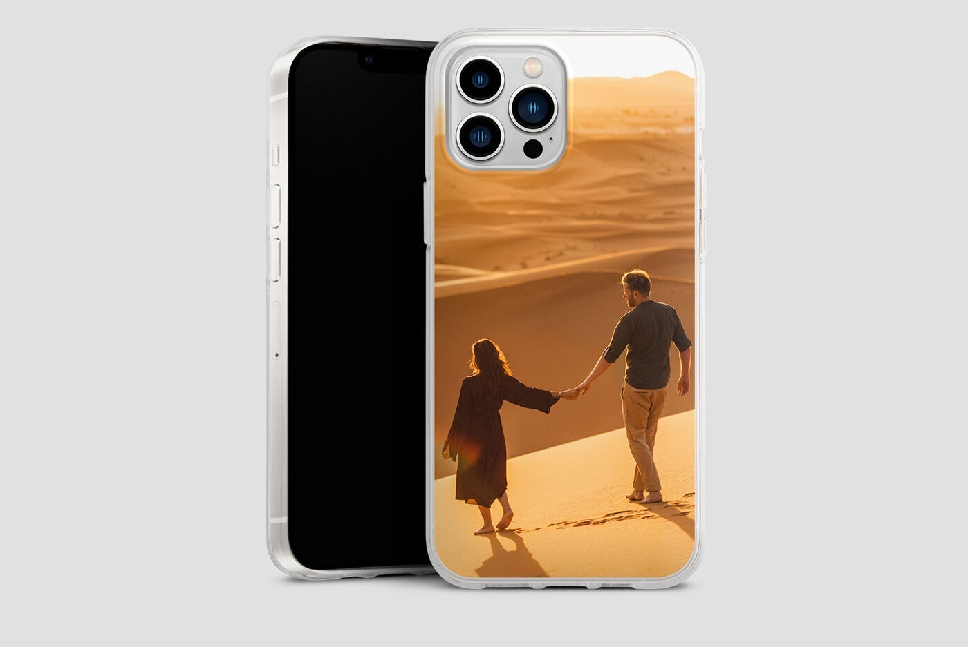 Una pareja toma de la mano y pasea por el desierto al atardecer, alegría y amor brillan en sus rostros.