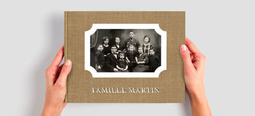 Dos manos sostienen un álbum CEWE con una foto familiar y el título "Familia Martín".