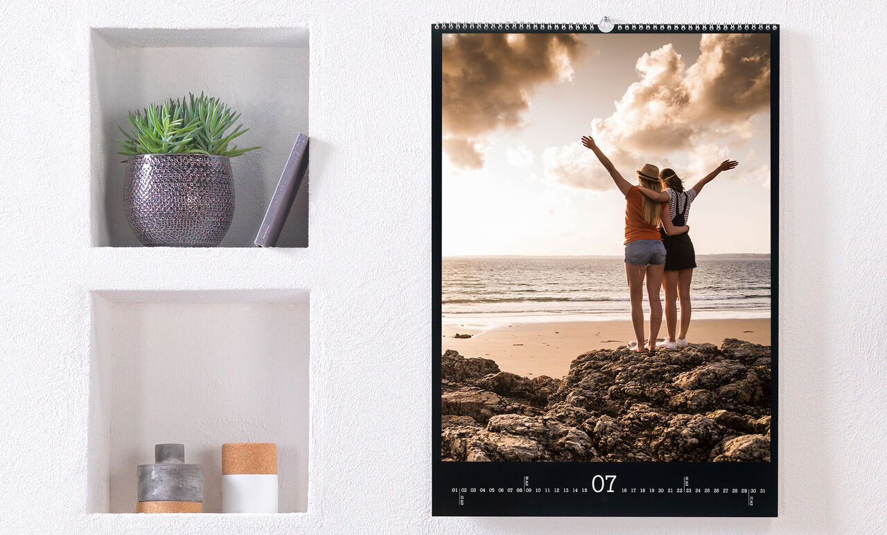 Dos mujeres celebran en la playa mirando las olas, calendario fotográfico.