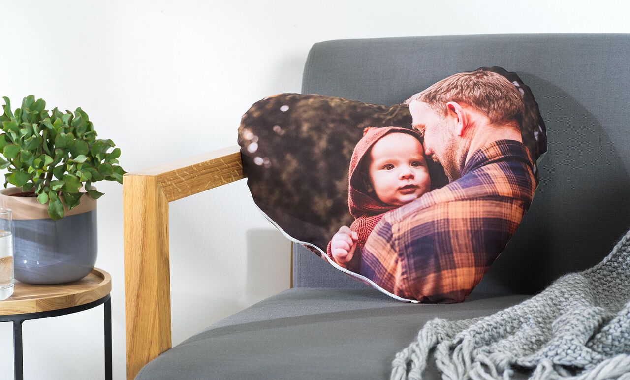 Cojín en forma de corazón con una foto de un hombre y un niño al aire libre.