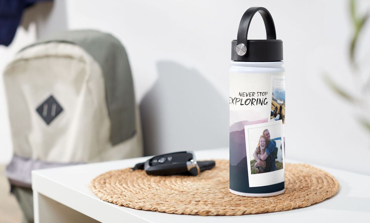 Botella personalizada con fotos y la inscripción "Never Stop Exploring" en una mesa
