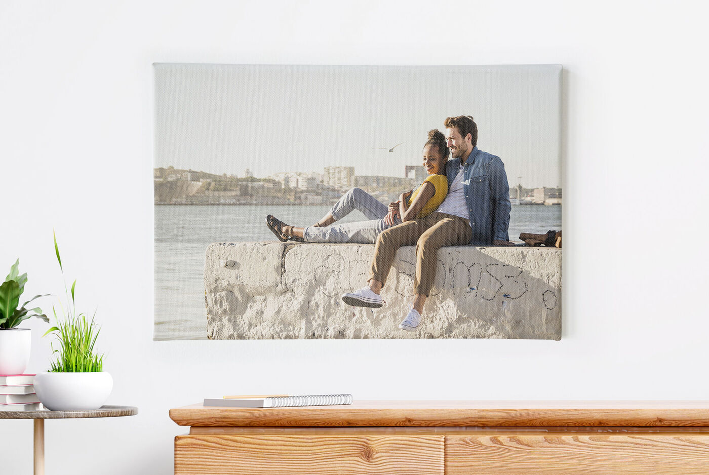 Una pareja sentada en el mar sobre un muro de piedra disfrutando de la vista
