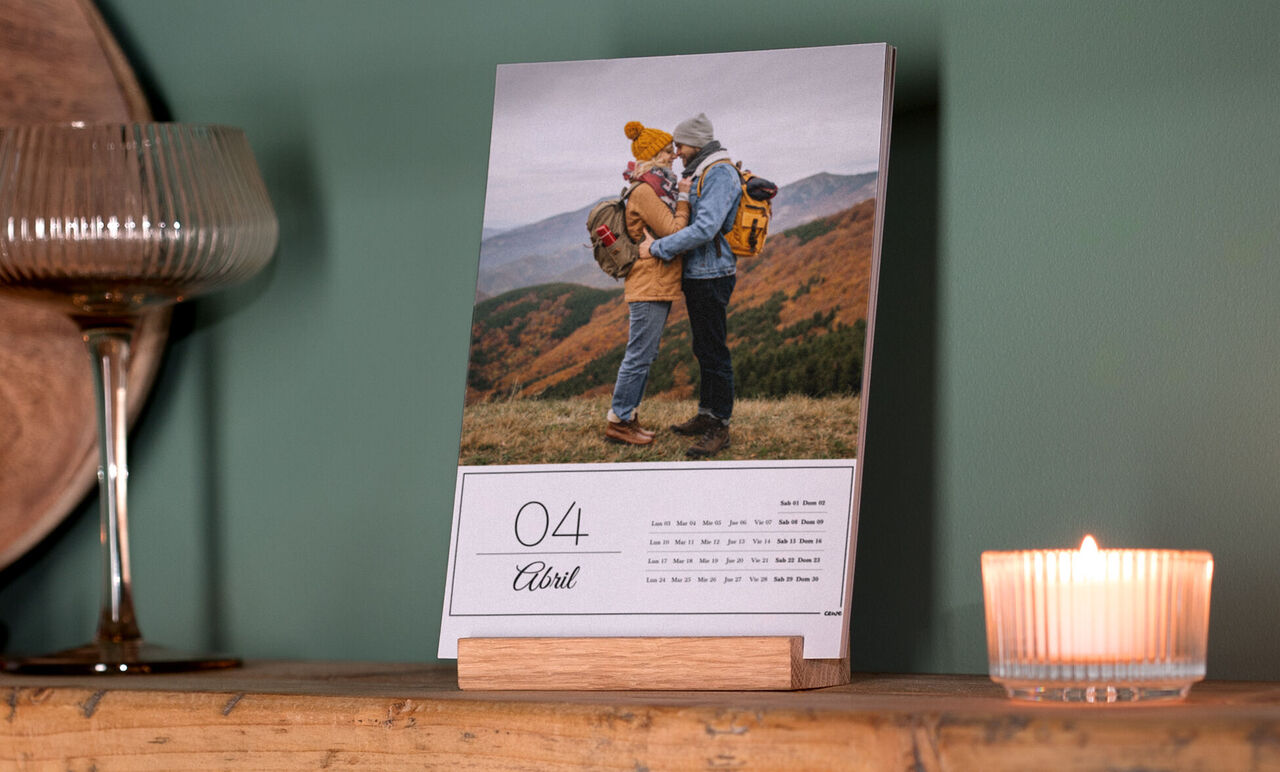 Una pareja se abraza en un calendario. De fondo hay suaves colinas y naturaleza tranquila, irradia amor.