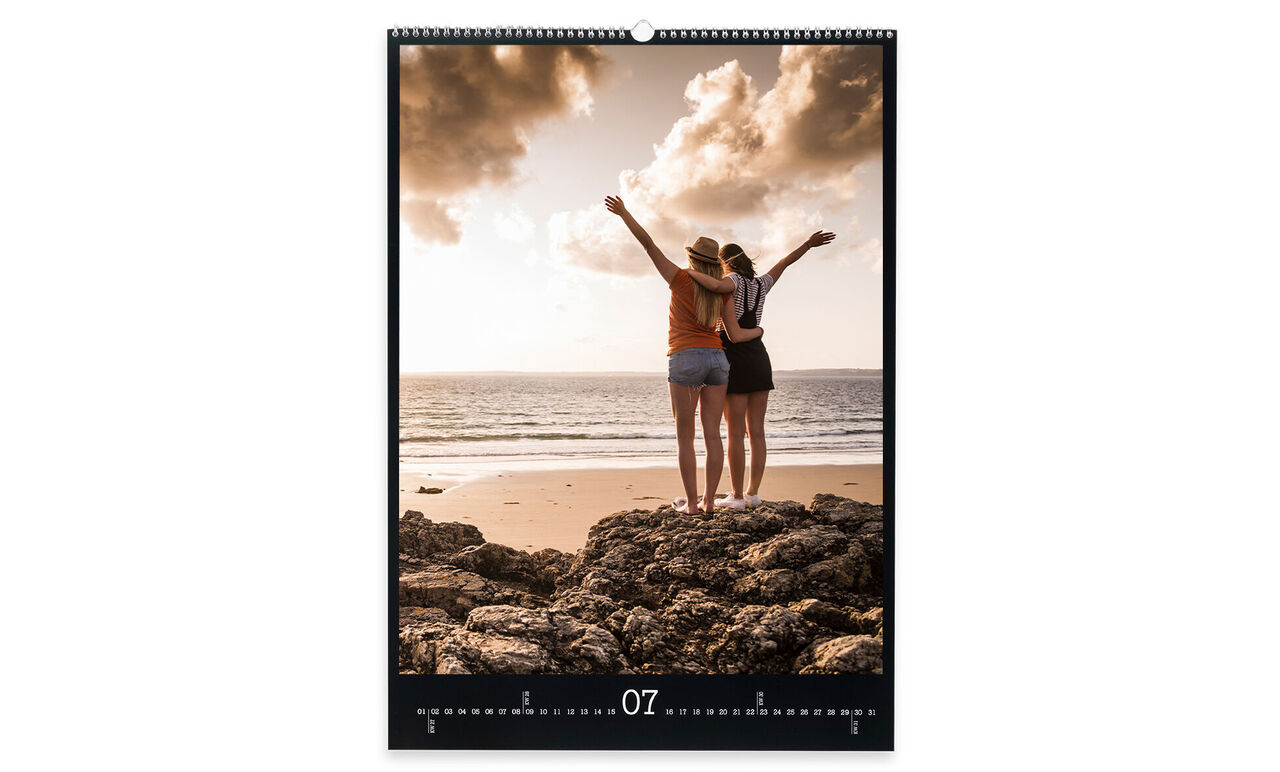 Dos mujeres en la playa disfrutando del atardecer, levantan los brazos y ríen.